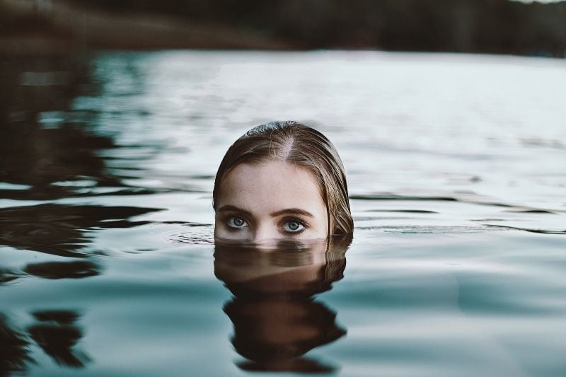 woman in water dipping in showing half of her face to the surface