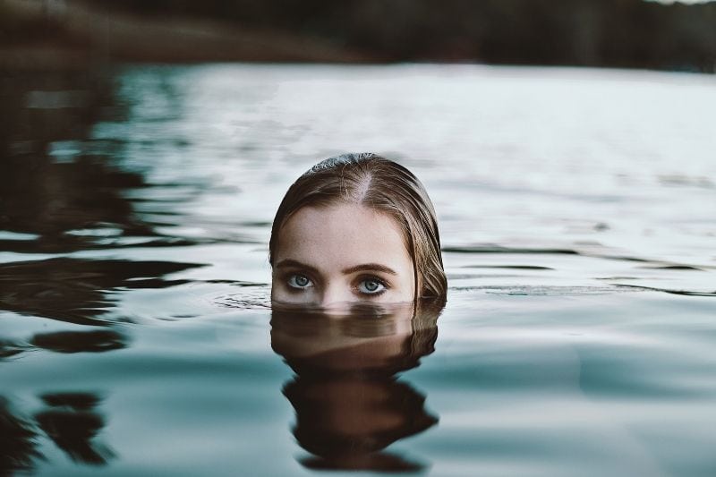 donna in acqua che si immerge mostrando metà del viso in superficie