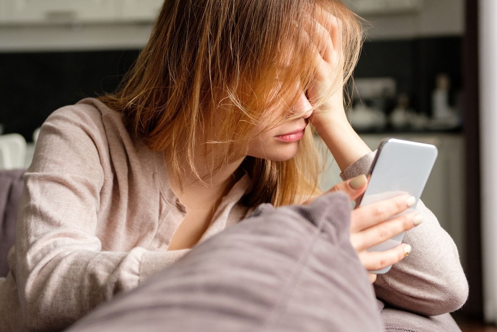 woman just woke up looking at the her smartphone leaning on her couch