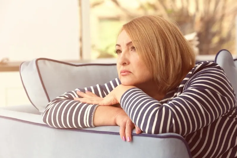 sad woman in striped top leaning on sofa