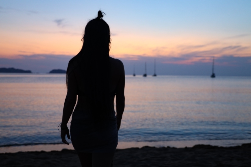 mujer mirando al mar durante la puesta de sol