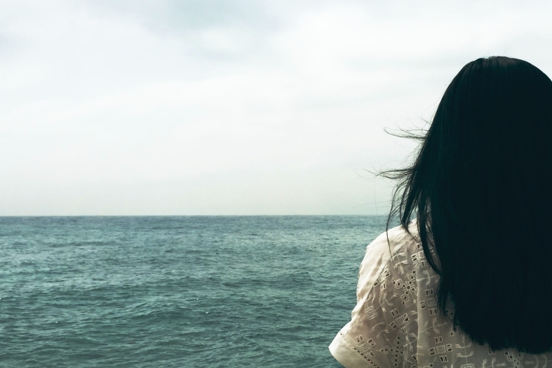 mujer con top blanco mirando al mar