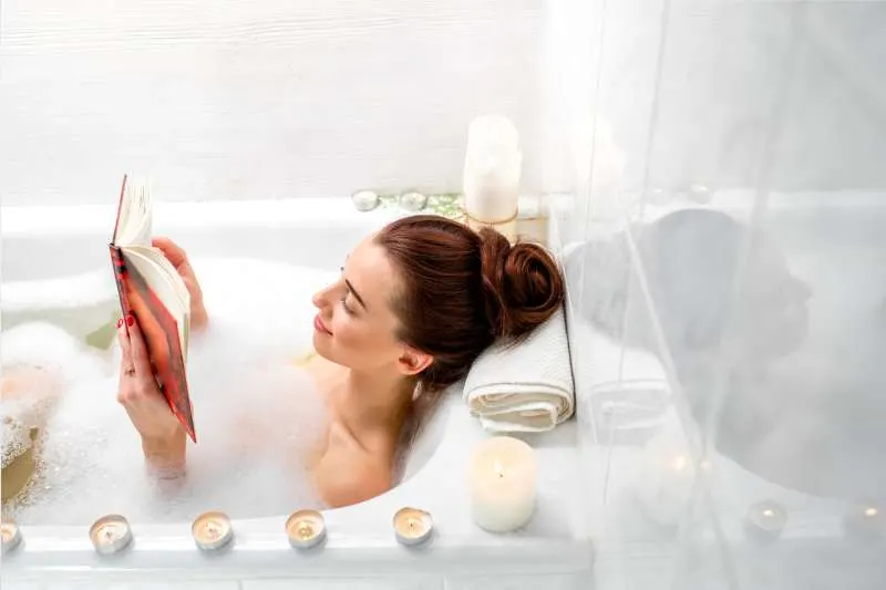 woman reading book while bathing in a bath tub
