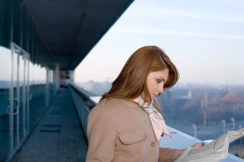 woman reading newspaper along the hallway of a building