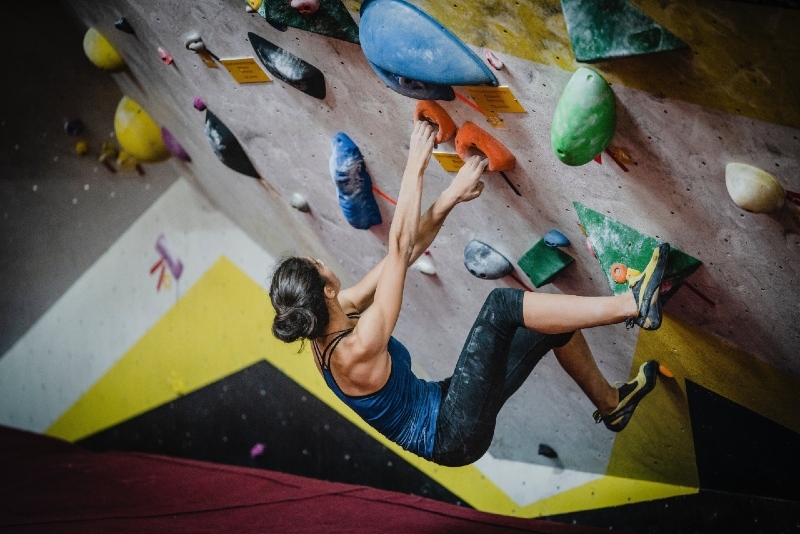 woman in blue top rock climbing inside building