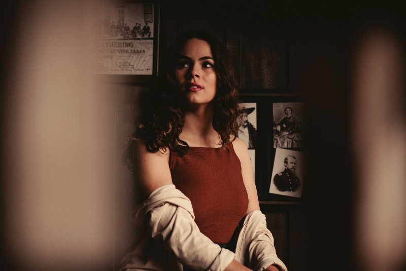 pensive woman with curly hair sitting near wall