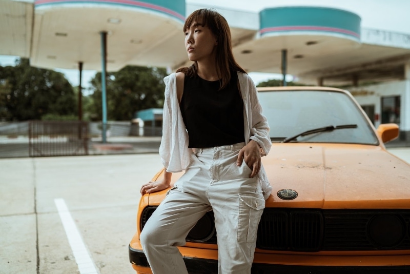 woman sitting on yellow car near gas station