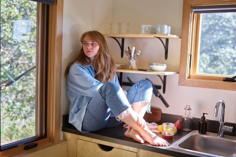donna con camicia di jeans seduta sul bancone della cucina