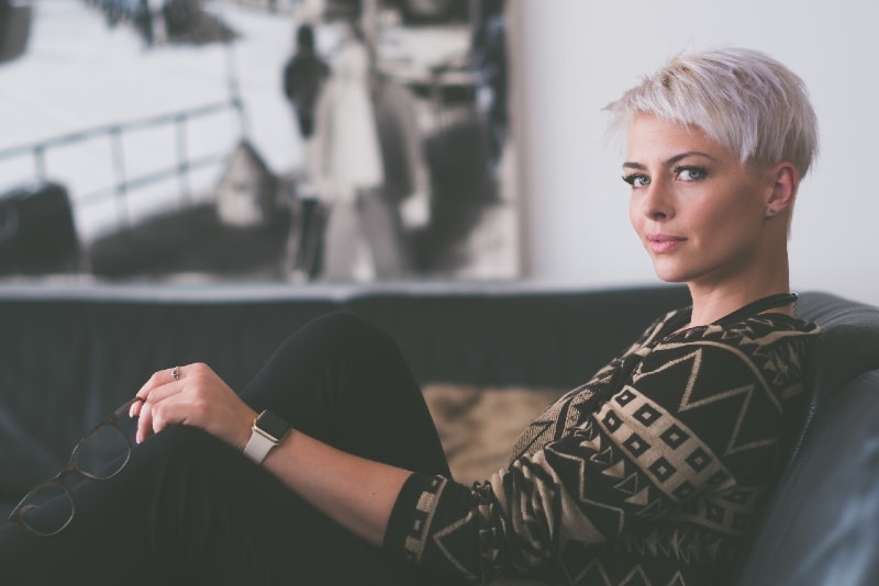 woman holding eyeglasses while sitting on sofa