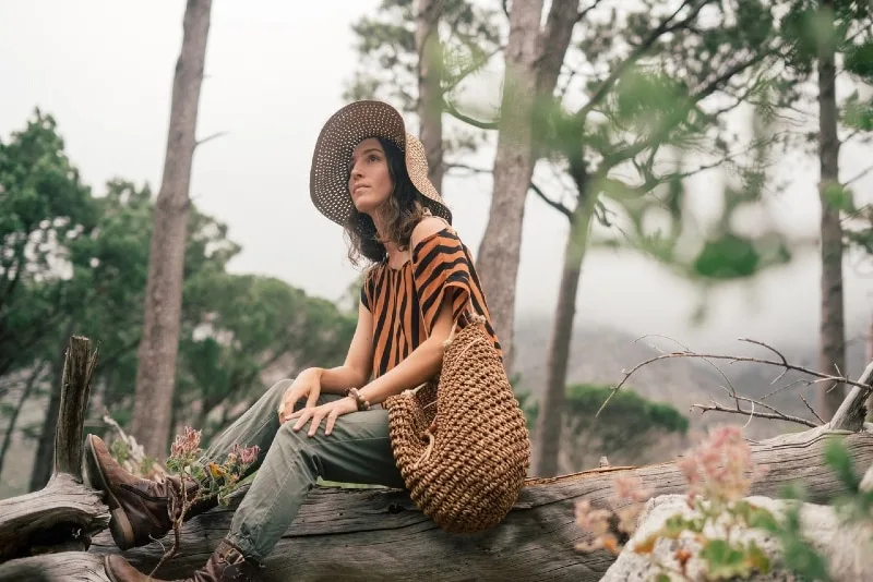 woman with hat sitting on wood log