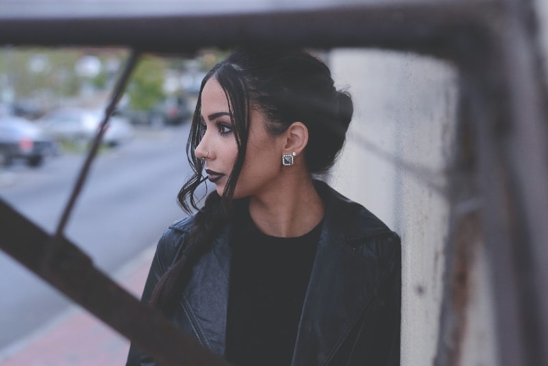 woman in black jacket standing beside road