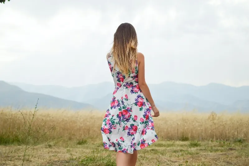 woman in floral dress standing in field