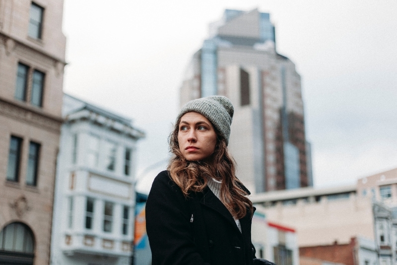 mujer con gorro de punto gris de pie cerca de un edificio