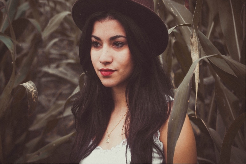 woman with hat standing near leafed plant