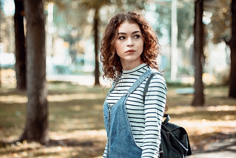 mulher com mochila preta junto a uma árvore