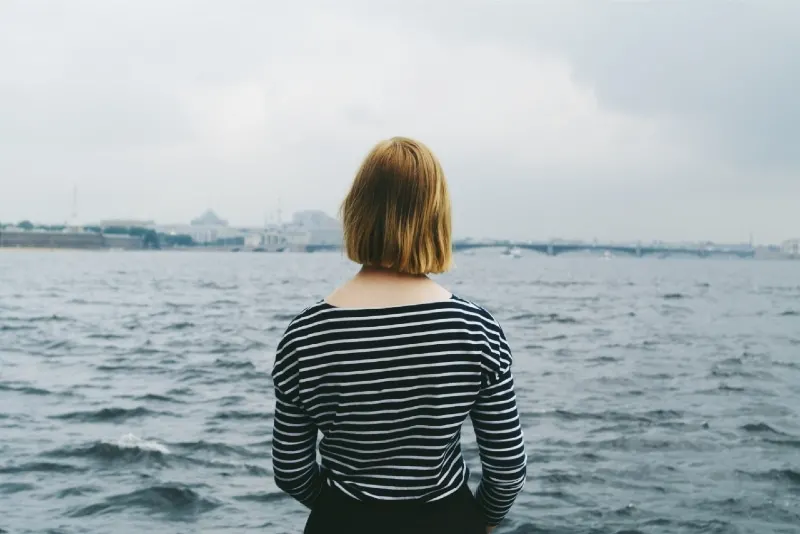 blonde woman in striped top standing near water