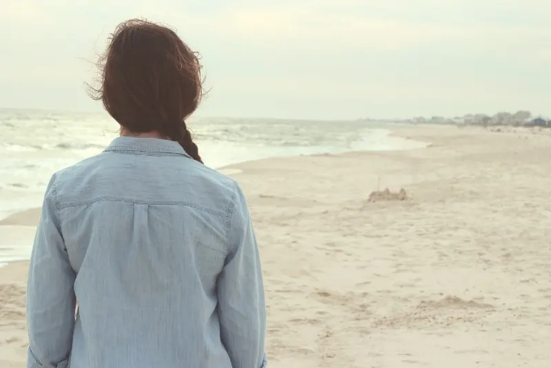 woman in denim shirt standing on beach