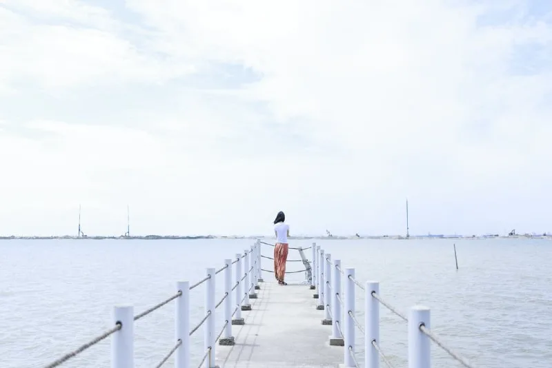 woman standing on dock looking at sea