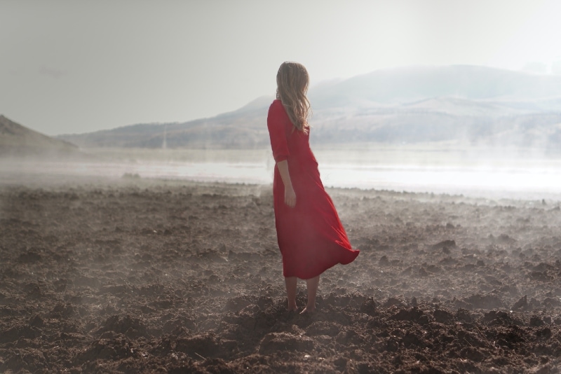 woman in red dress standing on brown soil
