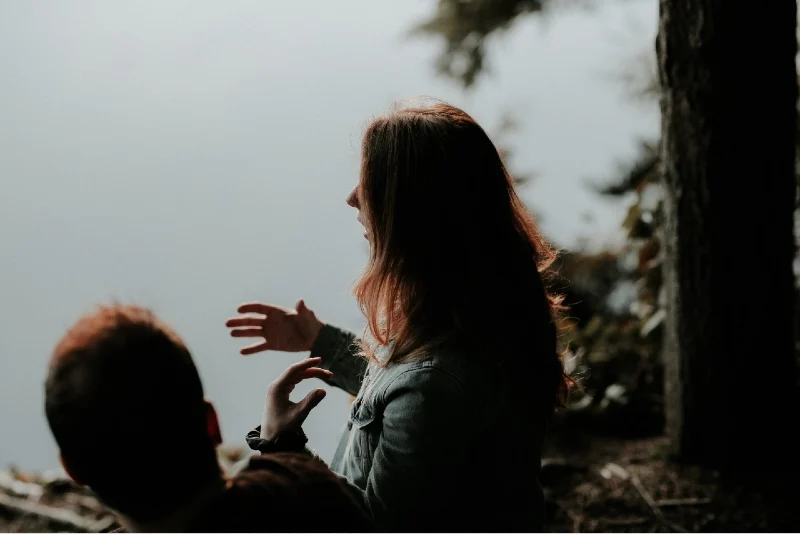 woman talking to man while sitting near water