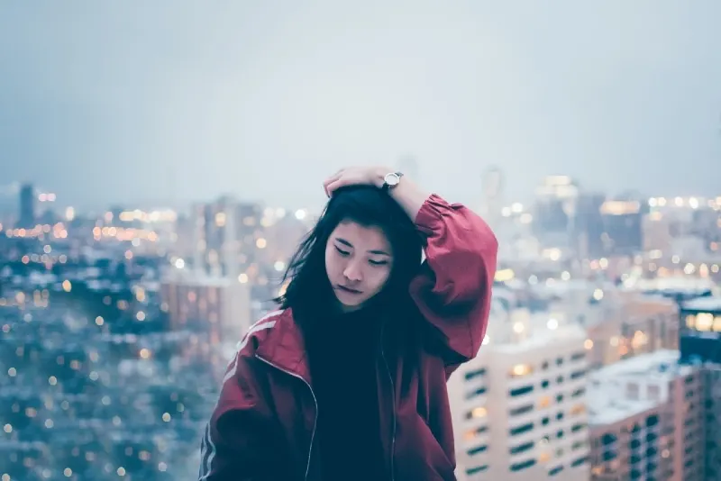 woman in red jacket touching her hair while standing outdoor