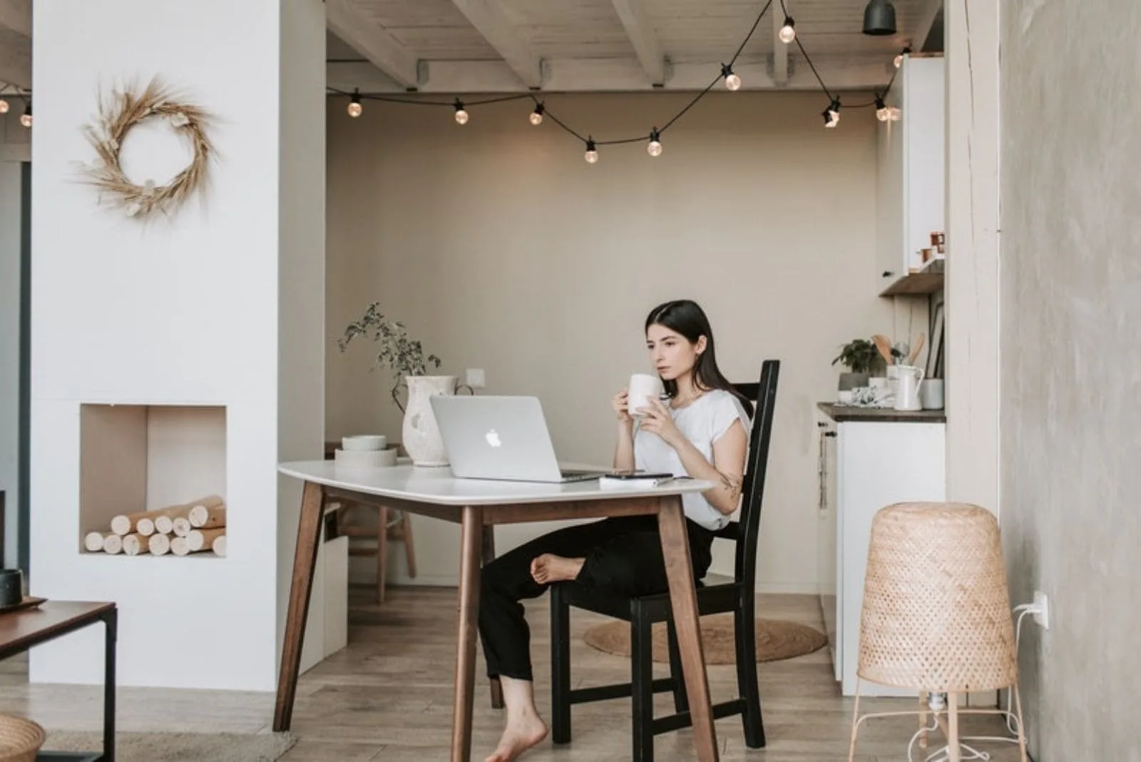 woman working at home drinking coffee with one foot rested on the chair