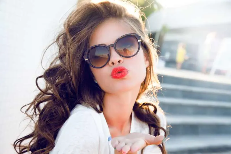 young attractive woman giving a kiss in air with red lips and an after salon hair