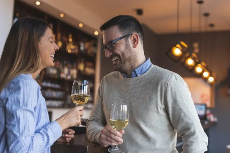 young couple dating standing near the counter drinking wine and laughing