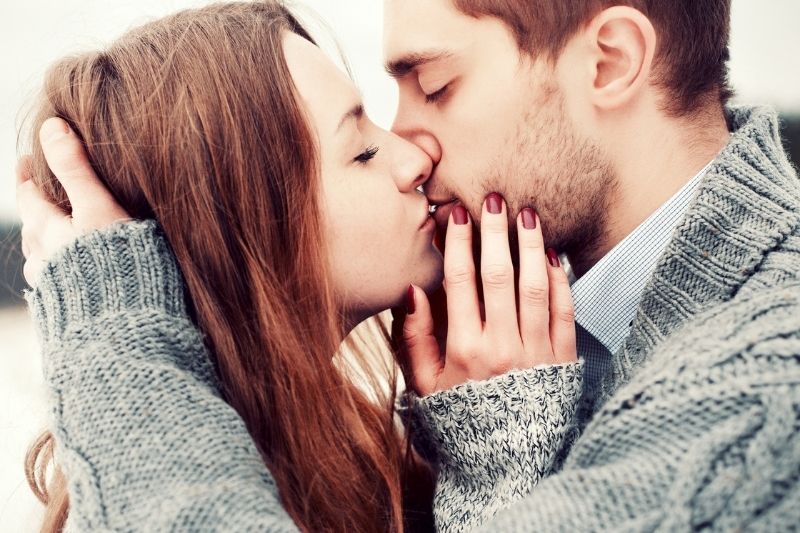 giovane coppia che si bacia donna che tiene il viso dell'uomo e uomo che tiene la testa di lei