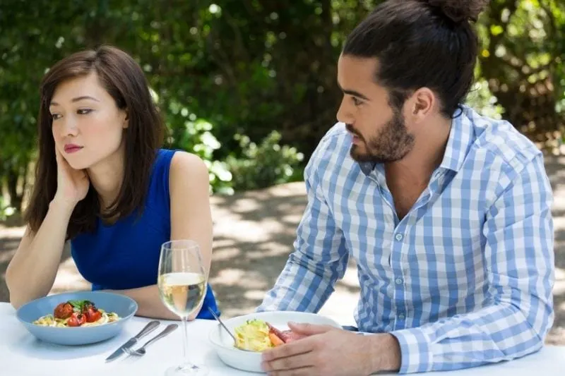young man looking at the upset woman in an outdoor restaurant