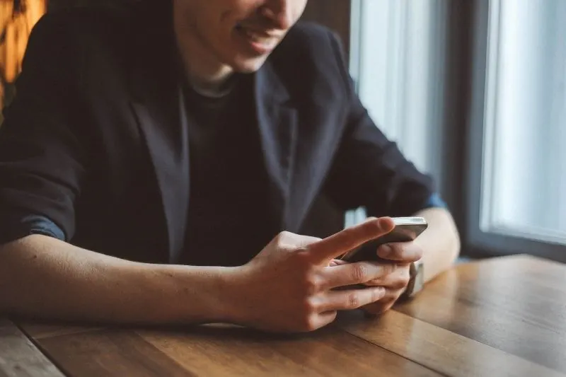 young man texting by the table in cropped image