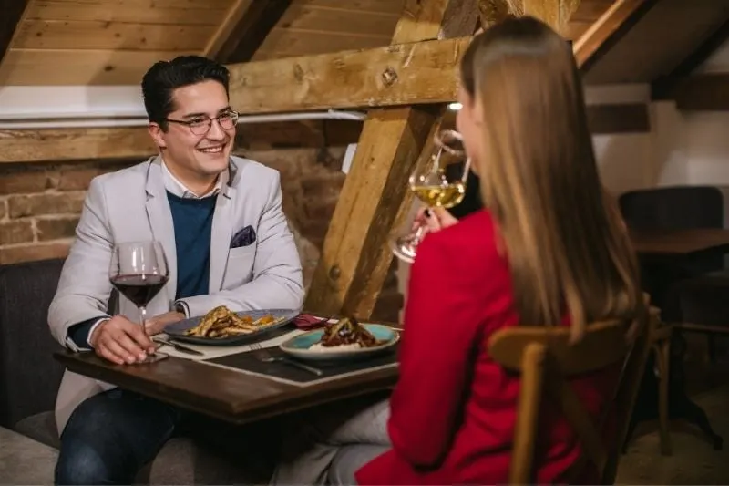 young modern couple on a first date eating dinner and having wine with the rear view of the woman