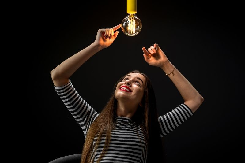 young woman inventor pointing at the illuminated lamp