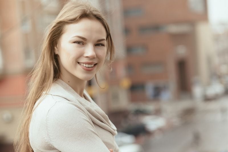 mulher jovem a sorrir, de pé na rua da cidade