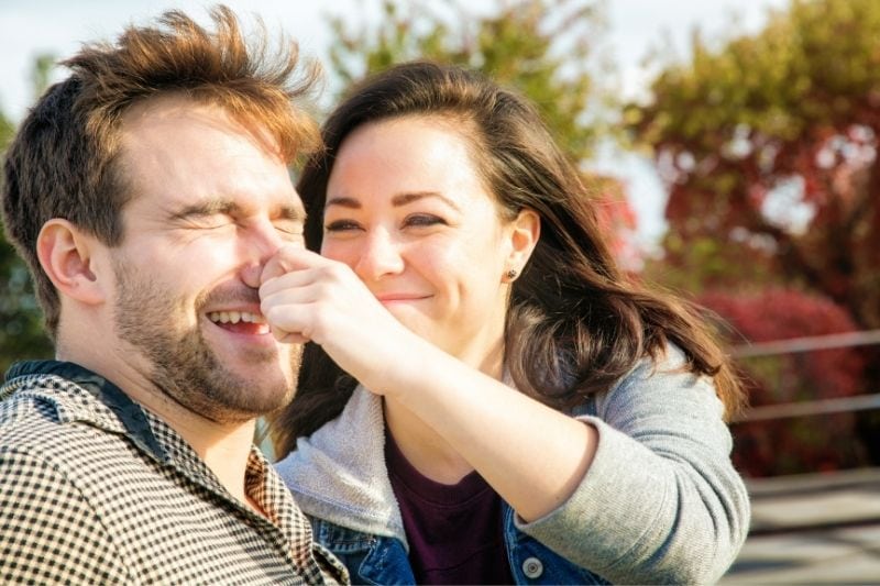 young woman teasing her boyfriend by pincing his nose