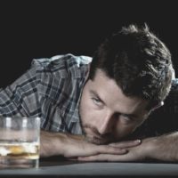 thoughtful man looking at glass of alcohol