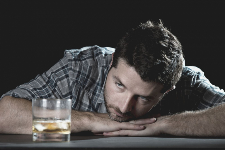 thoughtful man looking at glass of alcohol