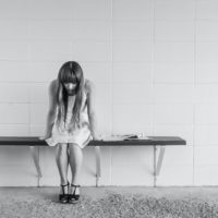 woman in white dress sitting on bench near wall