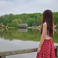 woman standing on bridge looking at water