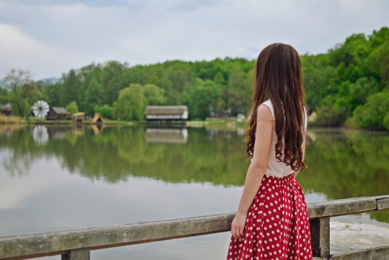 woman standing on bridge looking at water
