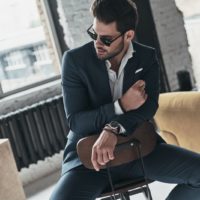 a handsome man in a suit is sitting on a chair