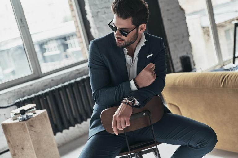 a handsome man in a suit is sitting on a chair
