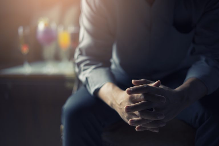 a sad man sits with his arms crossed