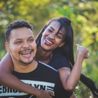 hombre feliz llevando mujer de pie al aire libre