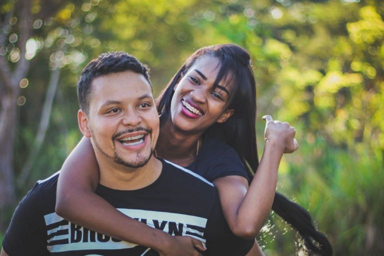 hombre feliz llevando mujer de pie al aire libre