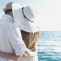 happy couple hugging facing the sea in a vacation to a tropical place