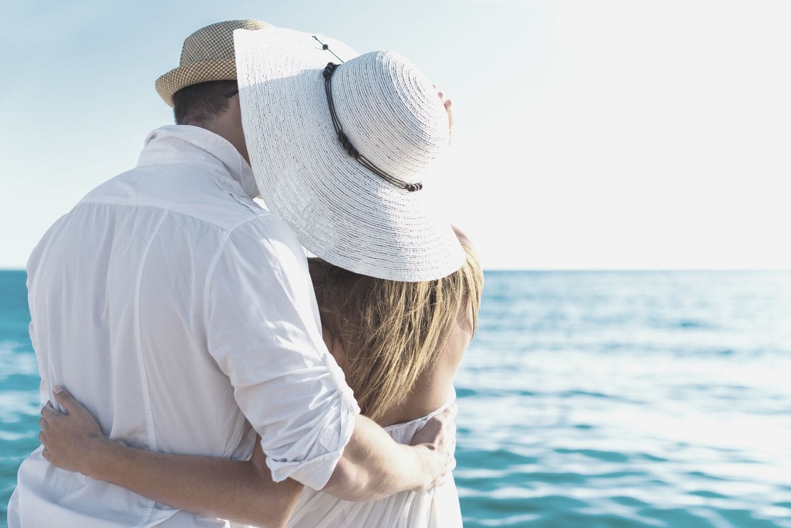 happy couple hugging facing the sea in a vacation to a tropical place