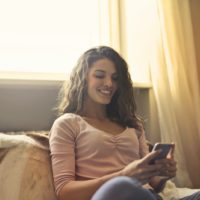 woman using smartphone while sitting on bed