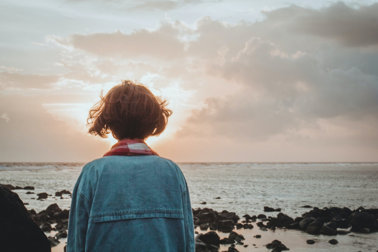 woman in denim jacket looking at sea