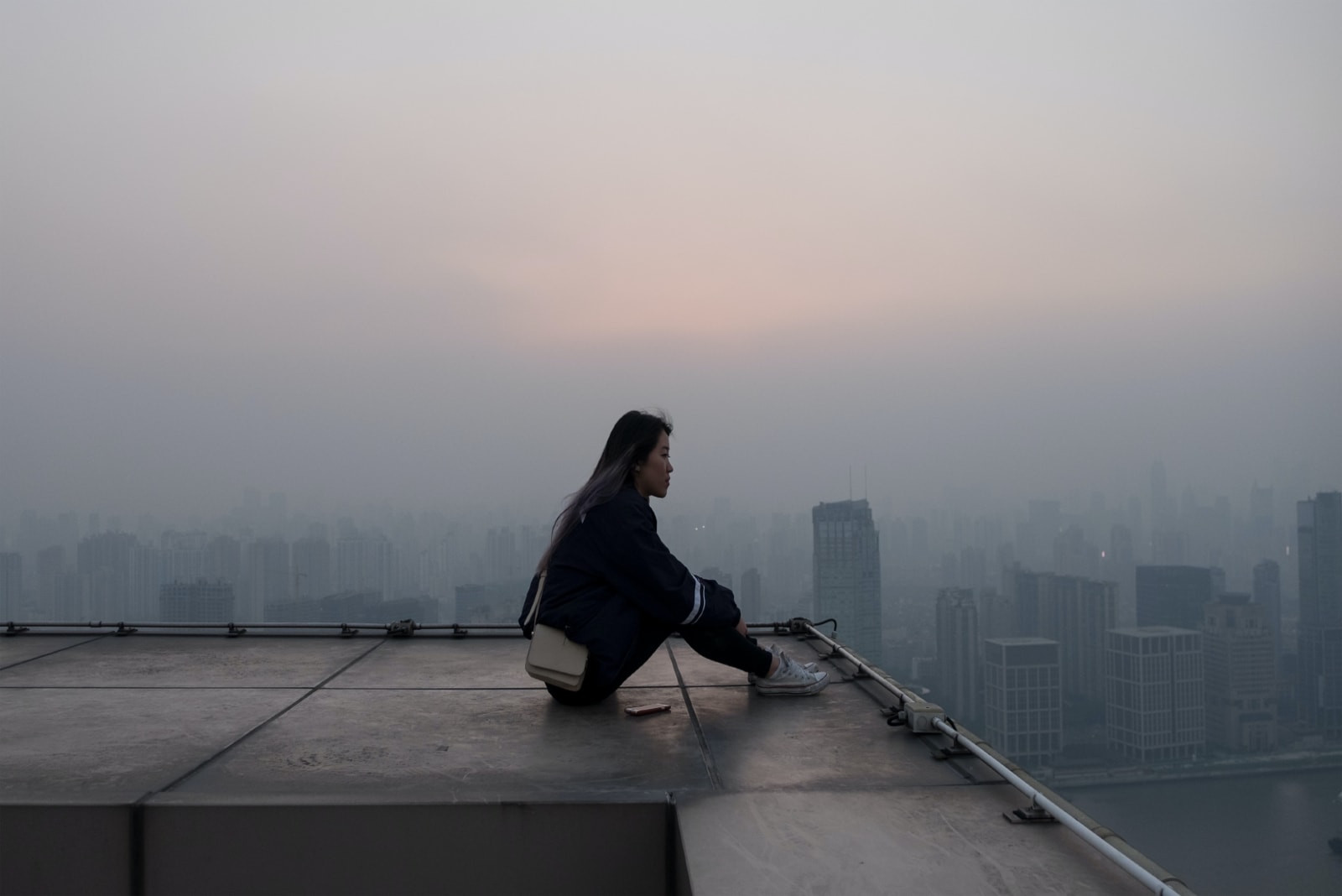 woman sitting on rooftop looking at buildings